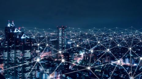 Kurstitelbild: Erleuchtete Großstadt bei Nacht, darüber entfaltet sich ein Netz aus Lichtpunkten mit transparenten Verbindungslinien.